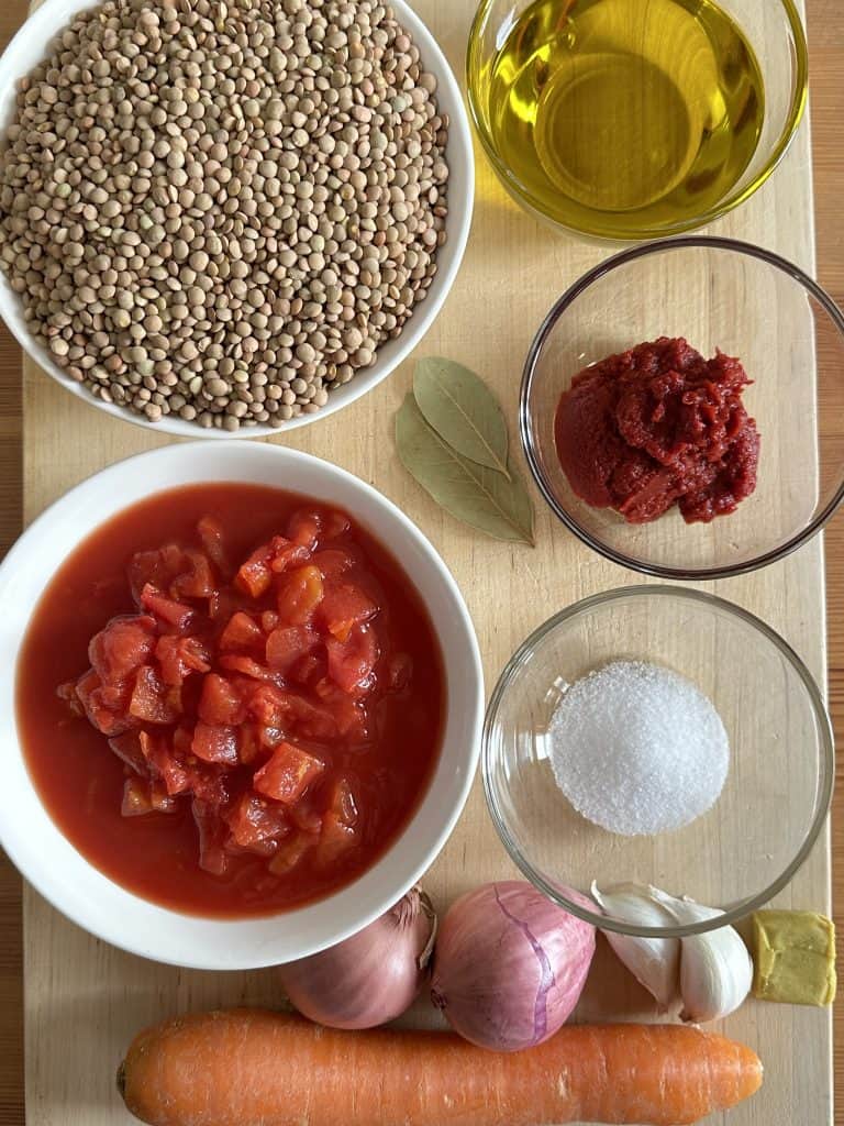 Ingredients to make Greek lentil soup laying out on a cutting board