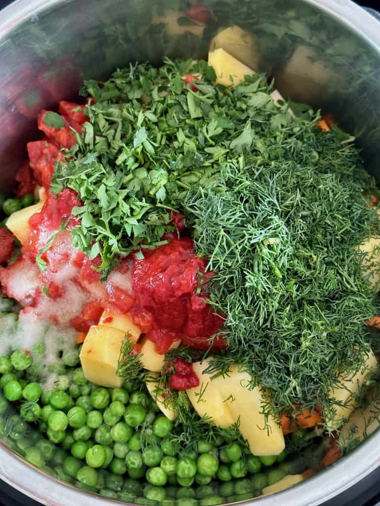 Greek peas, potatoes, herbs, and chopped vegetables in the Instant Pot before cooking