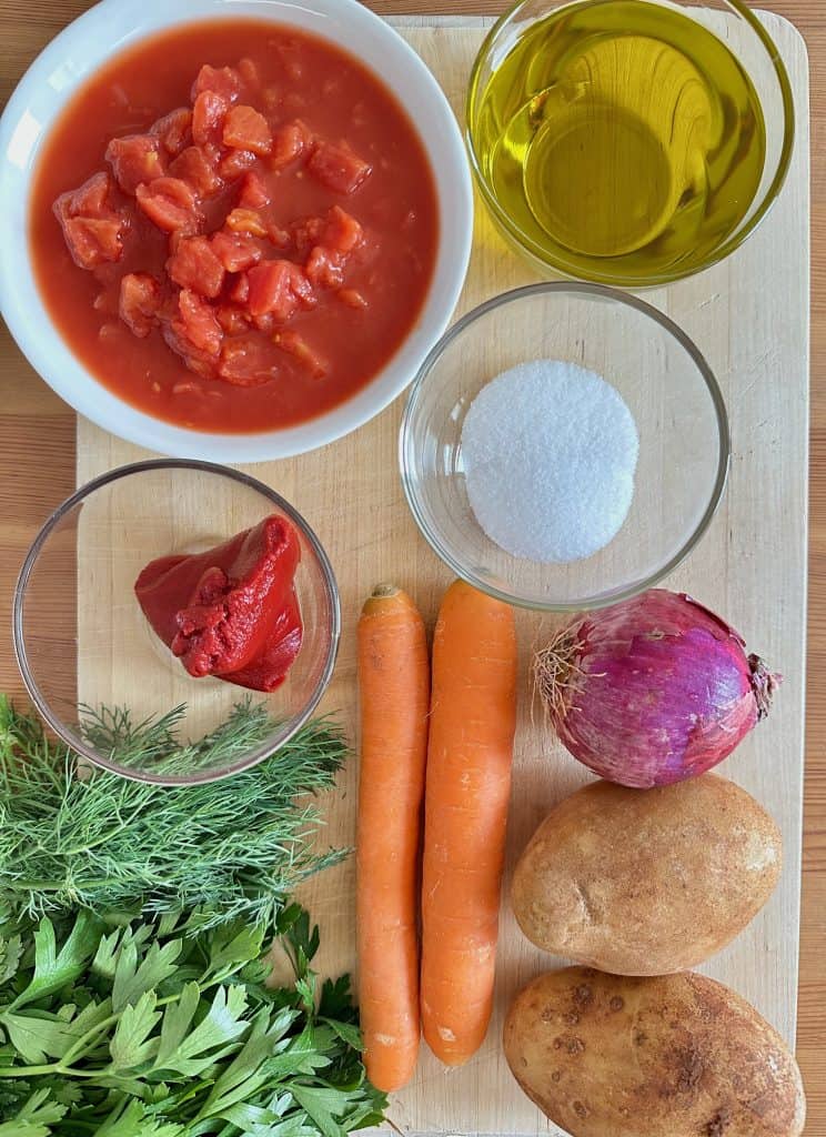 Ingredients used to make Instant Pot Arakas Kokkinistos on a wooden cutting board