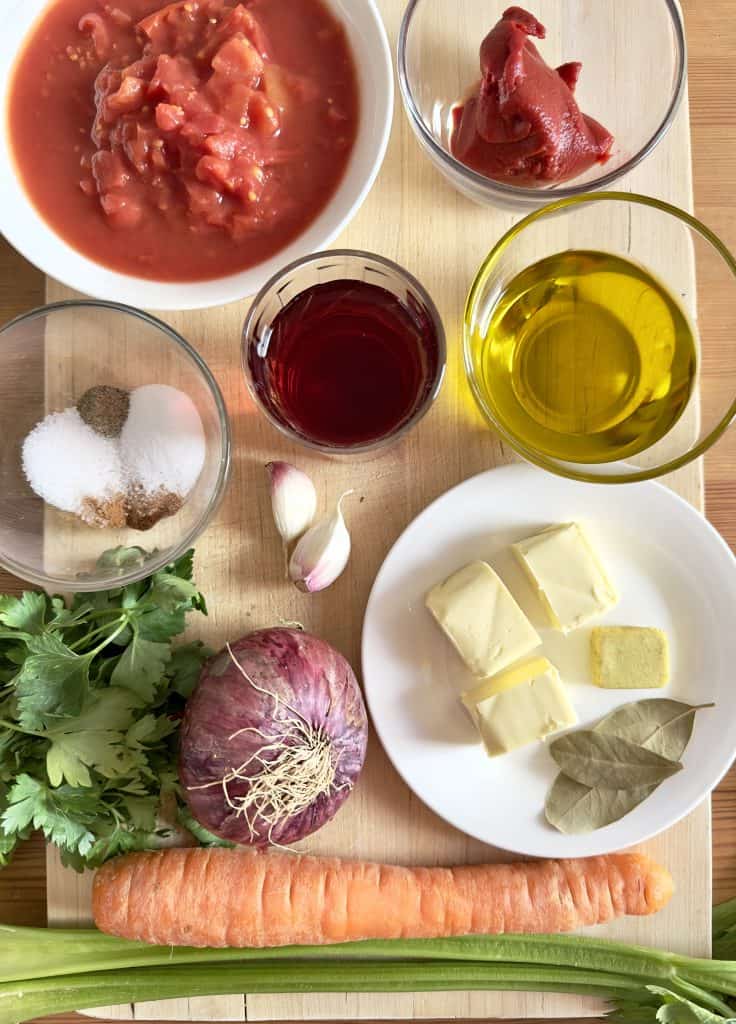 Ingredients for Greek Spaghetti and Meat Sauce recipe on a wooden cutting board