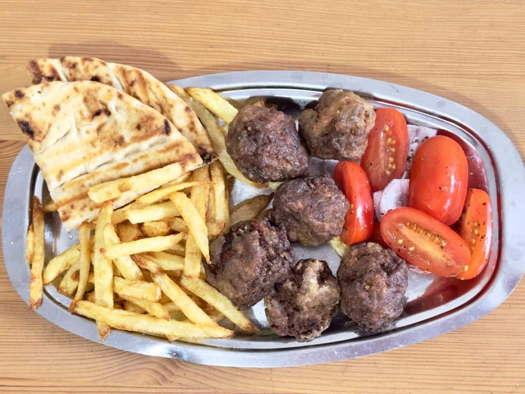 Greek Meatballs recipe Keftedes on a metal plate with french fries, grilled pita, and chopped tomatoes